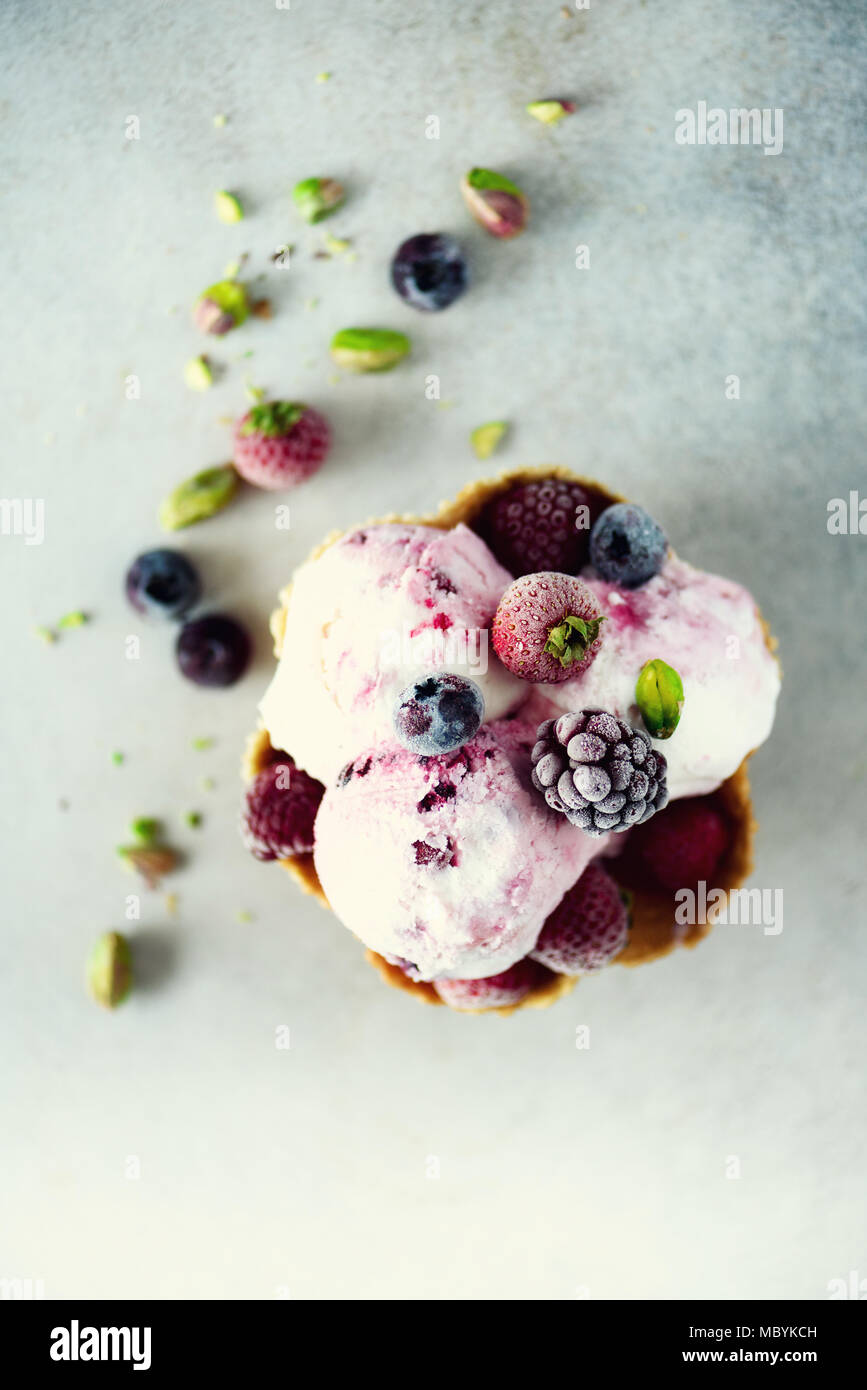 Rosa Eis mit Beeren, Erdbeeren, Blaubeeren, Himbeeren, Pistazien im Waffle basket. Sommer essen Konzept, kopieren. Gesund glutenfreie Obst Eis Stockfoto