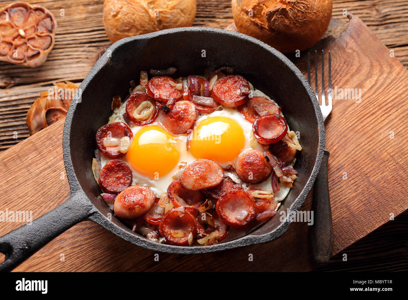 Spiegeleier mit Wurst und Zwiebeln in der Pfanne Stockfoto