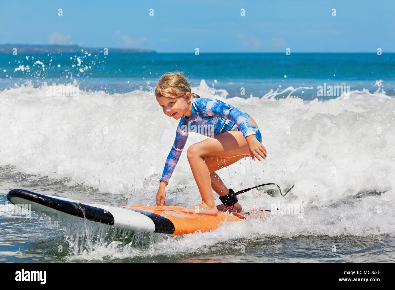 Happy Baby Mädchen - junge Surfer Fahrt auf Surfboard mit Spaß auf sea wave aktive Familie Lifestyle, Kids Outdoor Wassersport Lektionen und Aktivitäten am Strand Stockfoto