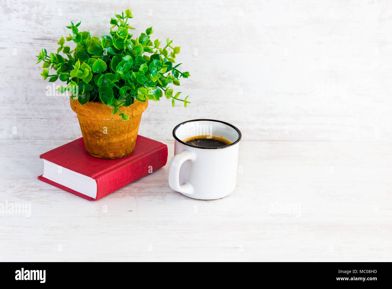 Kleine rote Buch, Kaffeetasse und grüne Blume im rustikalen Keramik Topf. Weiß Holz- Hintergrund, kopieren. Stockfoto
