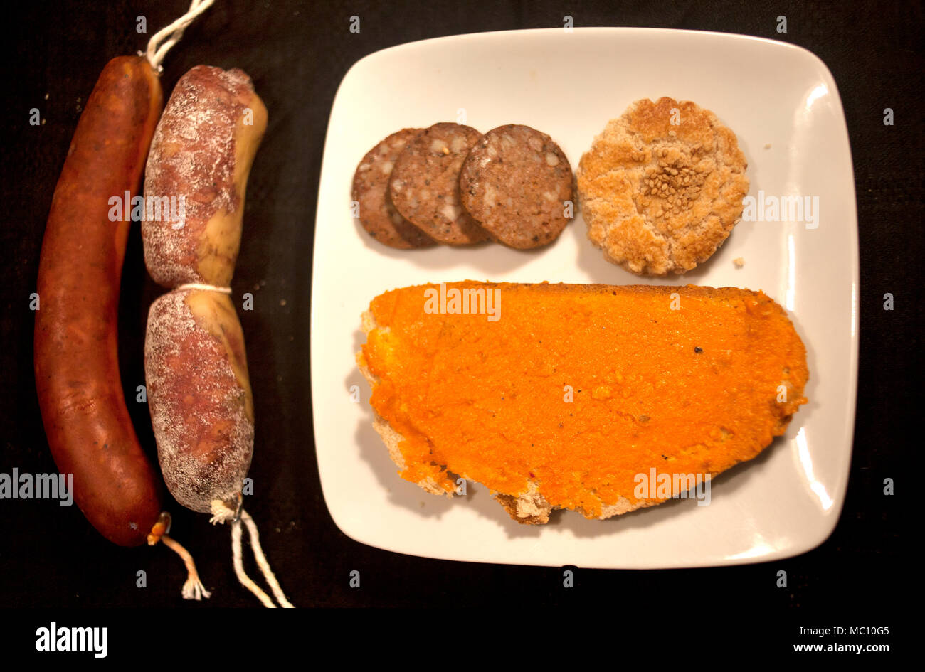 Wurst (Chorizo), Salami (salchichon), Blutwurst (morcilla) und einen Toast mit Schmalz von iberischen Schweinen und ein Cookie in Prado del Rey, Sierra de Graz Stockfoto