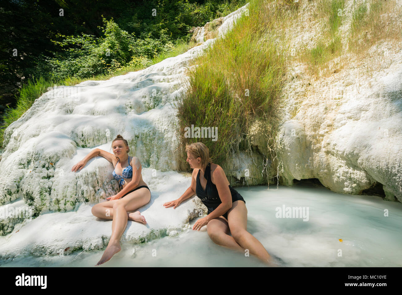 Zwei Frauen, die Fossa Bianca, weiße Wal, Calciumcarbonat Hot Springs und travertinbecken in Bagni San Filippo, der südlichen Toskana, Italien, Euro Stockfoto