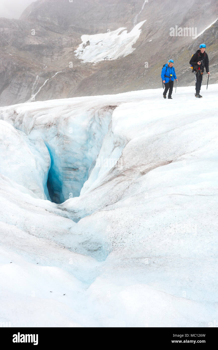 Zwei Personen Trek über eine eisige Gletscher Vergangenheit eine gefährliche Gletscherspalte während einer touristischen Abenteuer, Juneau Icefield, Juneau, Alaska, USA Stockfoto
