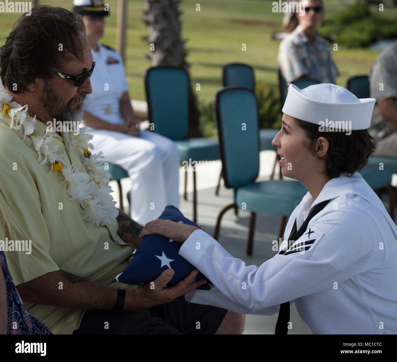 180119-N-ND 356-0070 Pearl Harbor (Jan. 19, 2018) ein Matrose zu Joint Base Pearl Harbor-Hickam Marine Ehrungen und Zeremonien Loslösung zugeordnet präsentiert die amerikanische Flagge zu Dennis Schwarz, Neffe von Mine Countermeasure Machinist's Mate First Class Frank Zylowski, ein Pearl Harbor Überlebenden, während einer Esche-Streuung Preisverleihung auf der USS Arizona Memorial auf Ford Island. (U.S. Marine Foto von Mass Communication Specialist 3. Klasse Jessica O. Blackwell) Stockfoto