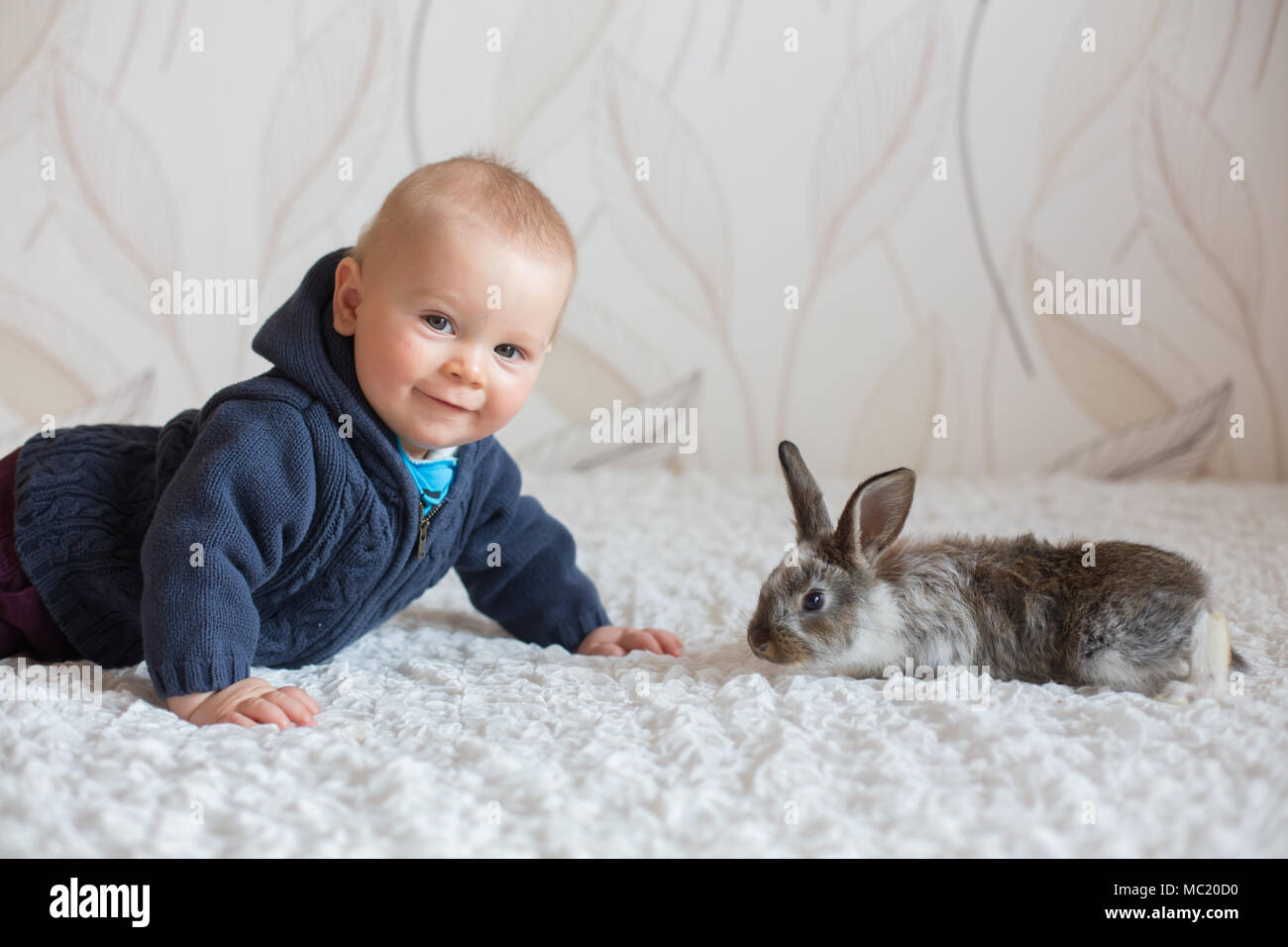 Süße kleine Baby Boy, spielen mit Kaninchen, Haustiere zu Hause Stockfoto
