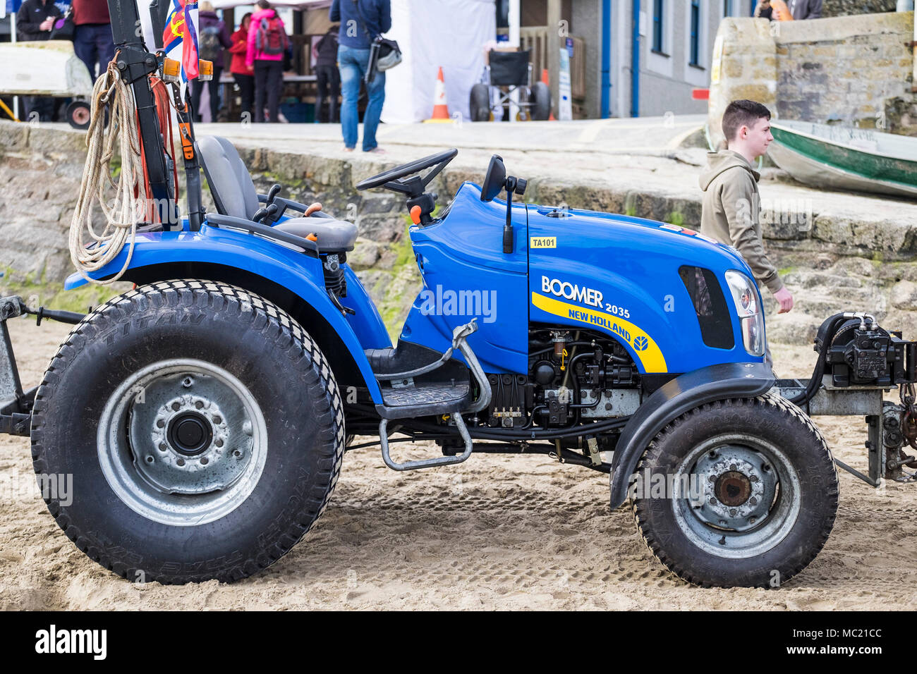 Ein Boomer 2035 New Holland Traktor auf dem Sand am Hafen von Newquay in Cornwall. Stockfoto