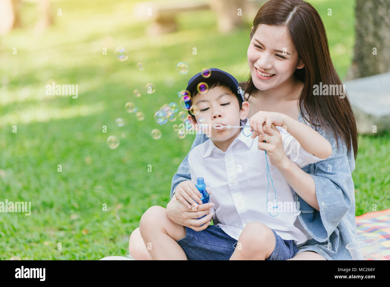 Schöne Asiatische junge Mutter mit ihrem Sohn glück Momente zusammen Spielen und Picknick im Park auf Urlaub für einzelne Mamma Konzept Stockfoto