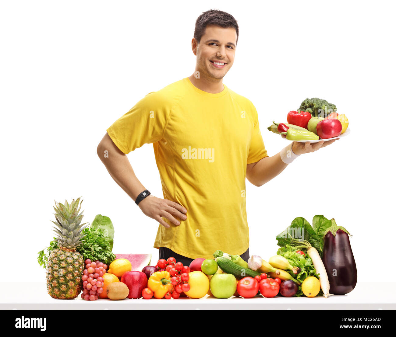 Junge Mann hinter einem Tisch mit Obst und Gemüse, die eine Platte auf weißem Hintergrund Stockfoto