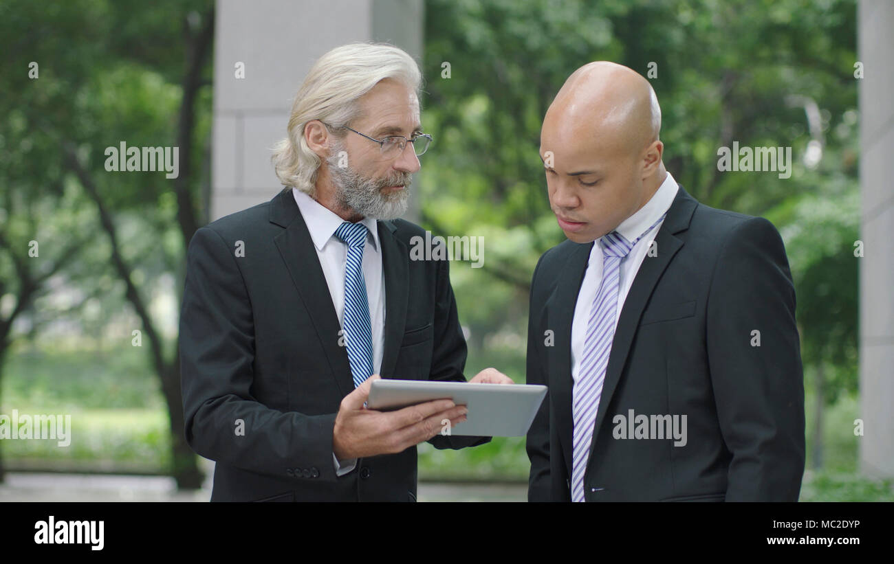 Kaukasische und Latino Führungskräfte diskutieren Geschäft mit digitalen Tablet. Stockfoto