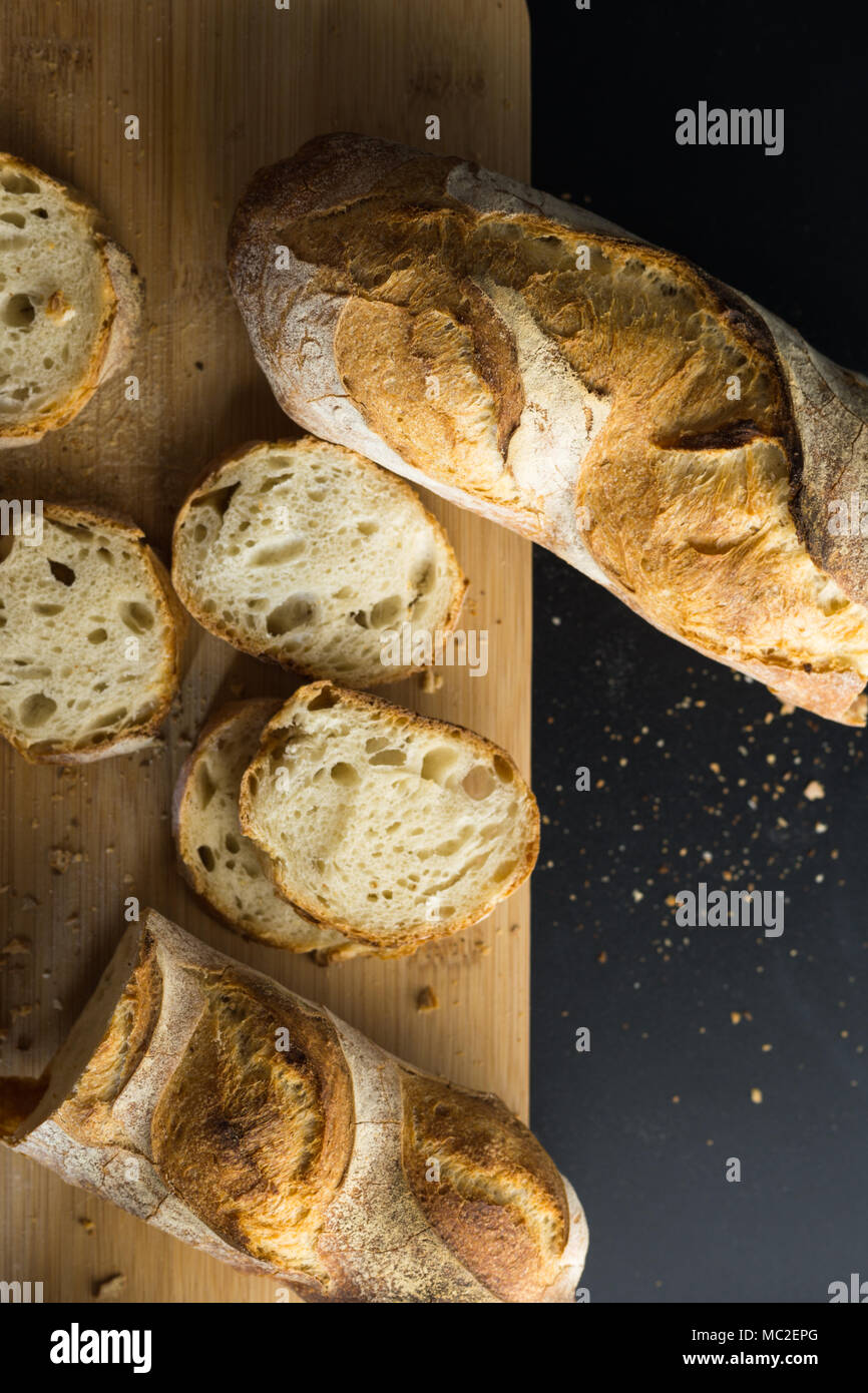 Französisches Brot - Baguette auf einem hölzernen Schneidebrett, Ansicht von oben geschnitten. Stockfoto