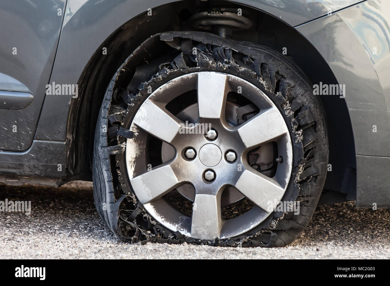 Sie zerstörte Reifen geblasen mit explodierte, geschreddert und beschädigte Gummi auf modernem SUV Automobil. Flache flache Reifen auf einer Leichtmetallfelge, riss öffnen Stockfoto
