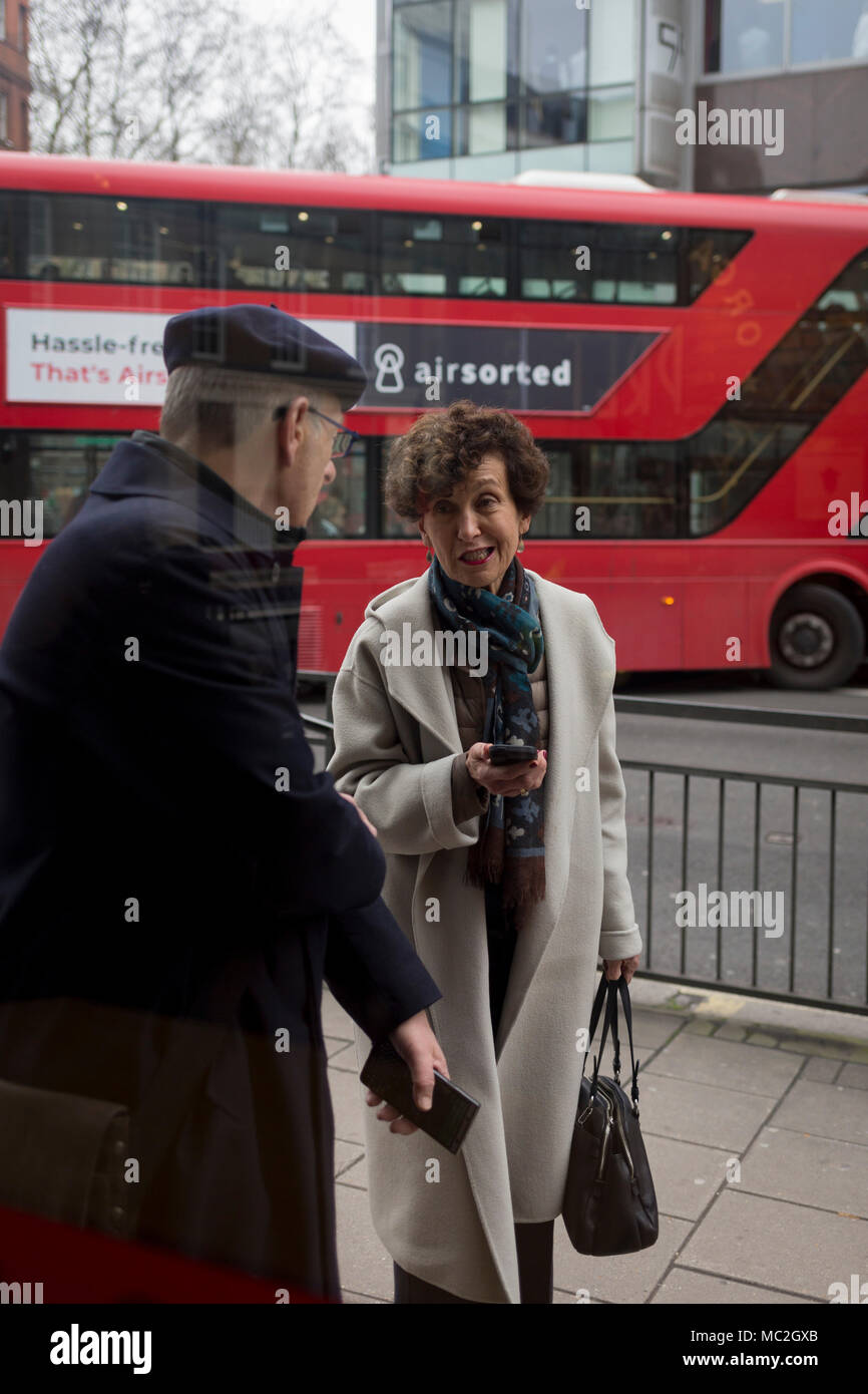 Zwei Menschen mit Handys halten eine physische Gespräch auf der Straße, am 11. April 2018 in London, England. Stockfoto