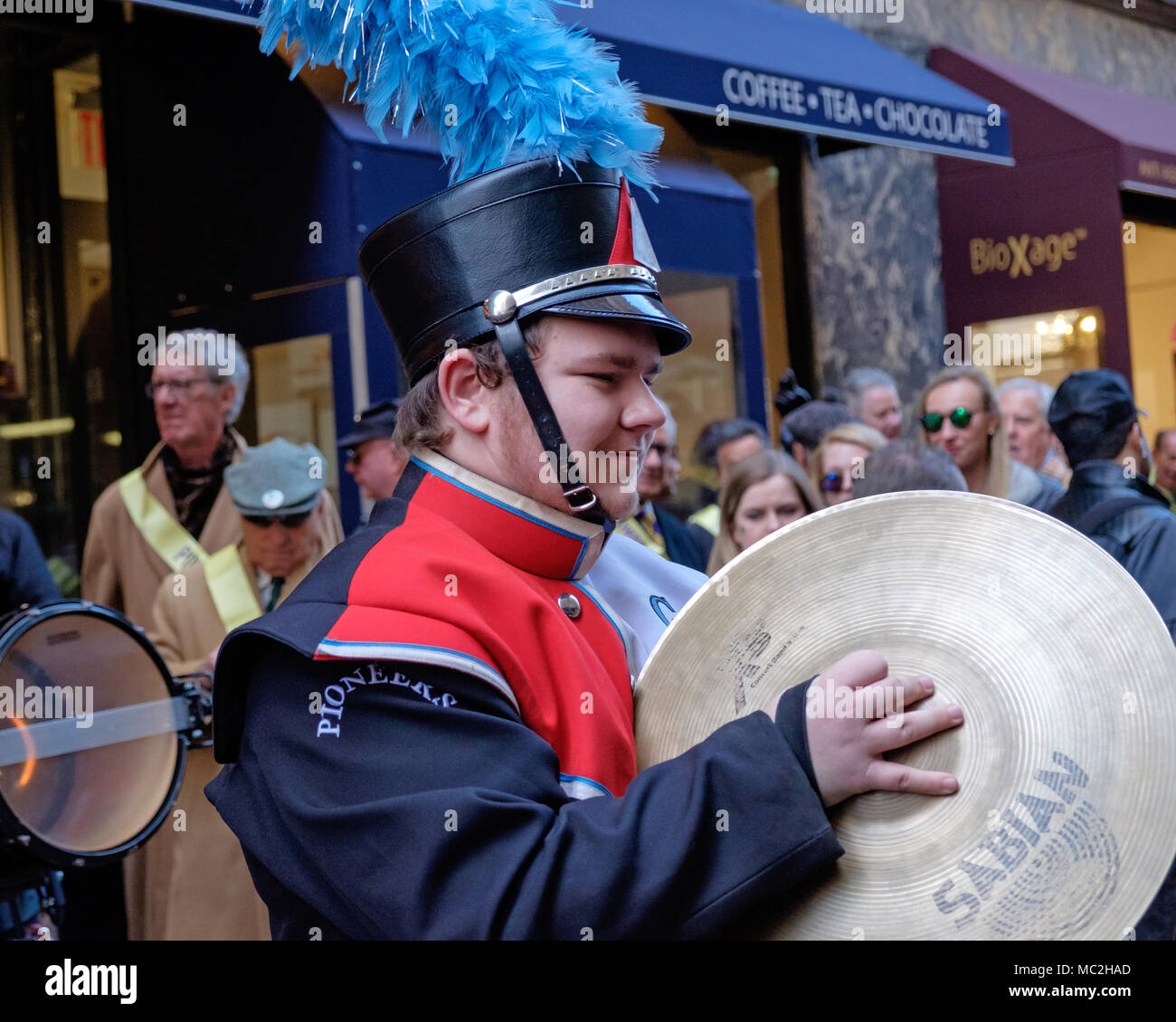 High School Junge mit Zimbeln in Marching Band, St. Patrick's Day Parade, New York, 2018. Rot, Weiß und Schwarz Band einheitlicher, schwarzer Hut, blaue Federn. Stockfoto