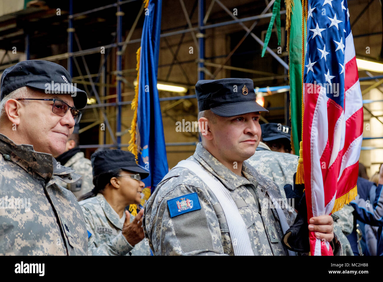 Zwei Männer März mit 88Th Brigade, New York Schutz in der St. Patrick's Day Parade, New York, 2018. Hält man die amerikanische Flagge. Uniformen, blauen Kappen. Close Up. Stockfoto