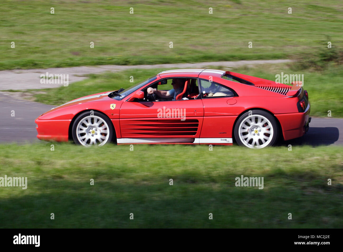 Rote Ferrari 348 modern Classic supercar im Profil (Seitenansicht) schnelles Fahren auf einer Landstraße. 348 wurde zuletzt Mitte Motor V8 von Enzo Ferrari entwickelt. Stockfoto