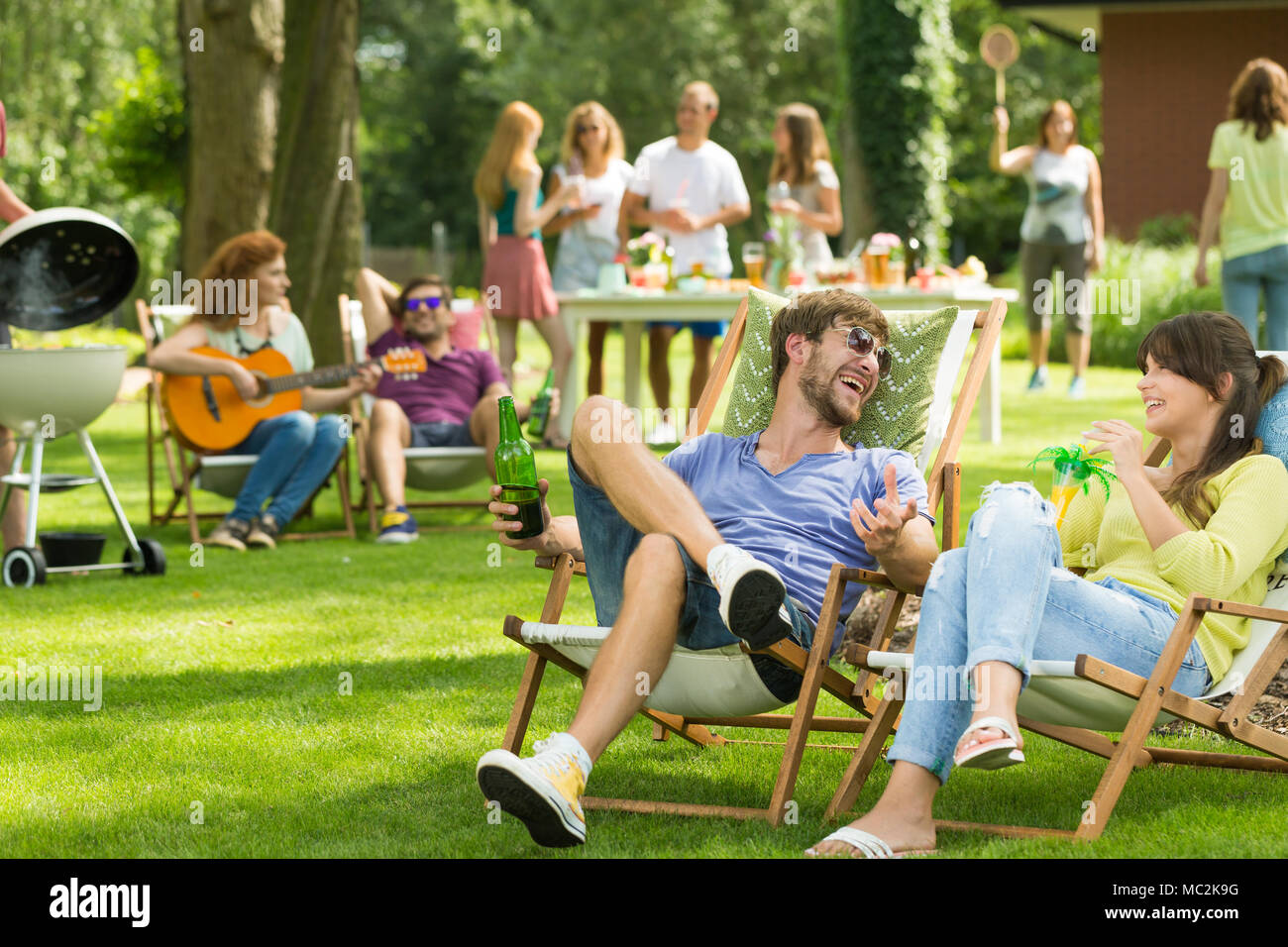 Freunde sitzen auf liegen und trinken Getränke beim Grillen im Garten mit  Freunden Stockfotografie - Alamy