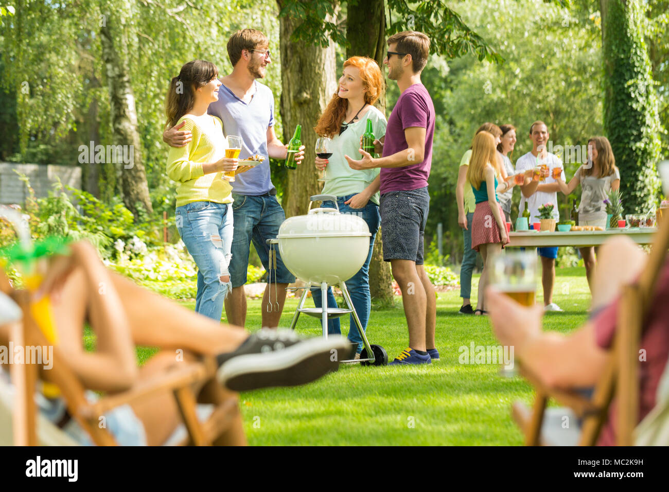 Gruppe von jungen Freunden sprechen, an einem sonnigen Tag, genießen Sommerferien Bier trinken und Grillen in der Natur Stockfoto