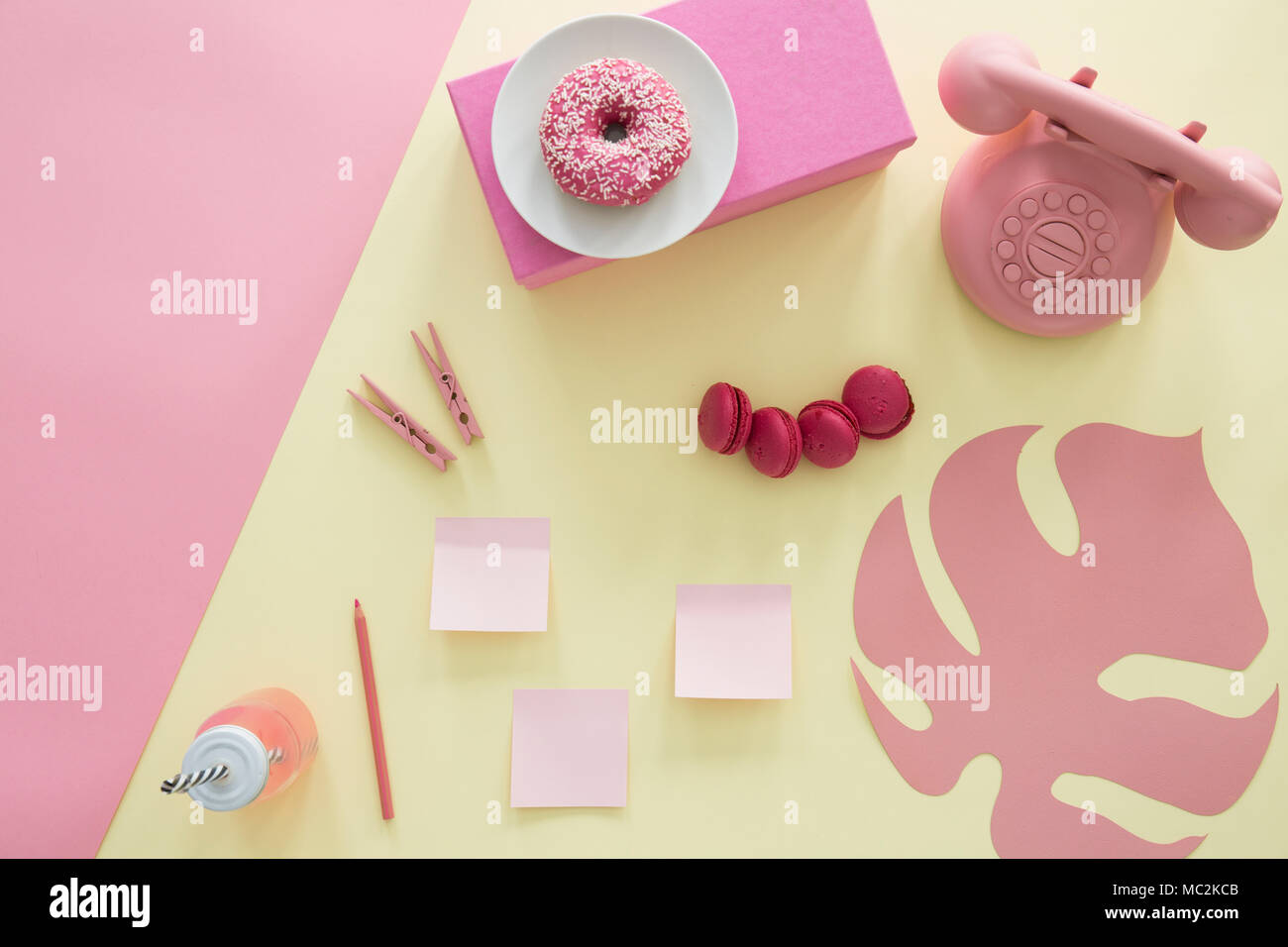 Kopieren Sie Speicherplatz auf rosa Hintergrund und Blatt, Donut und Telefon auf gelbem Hintergrund Stockfoto