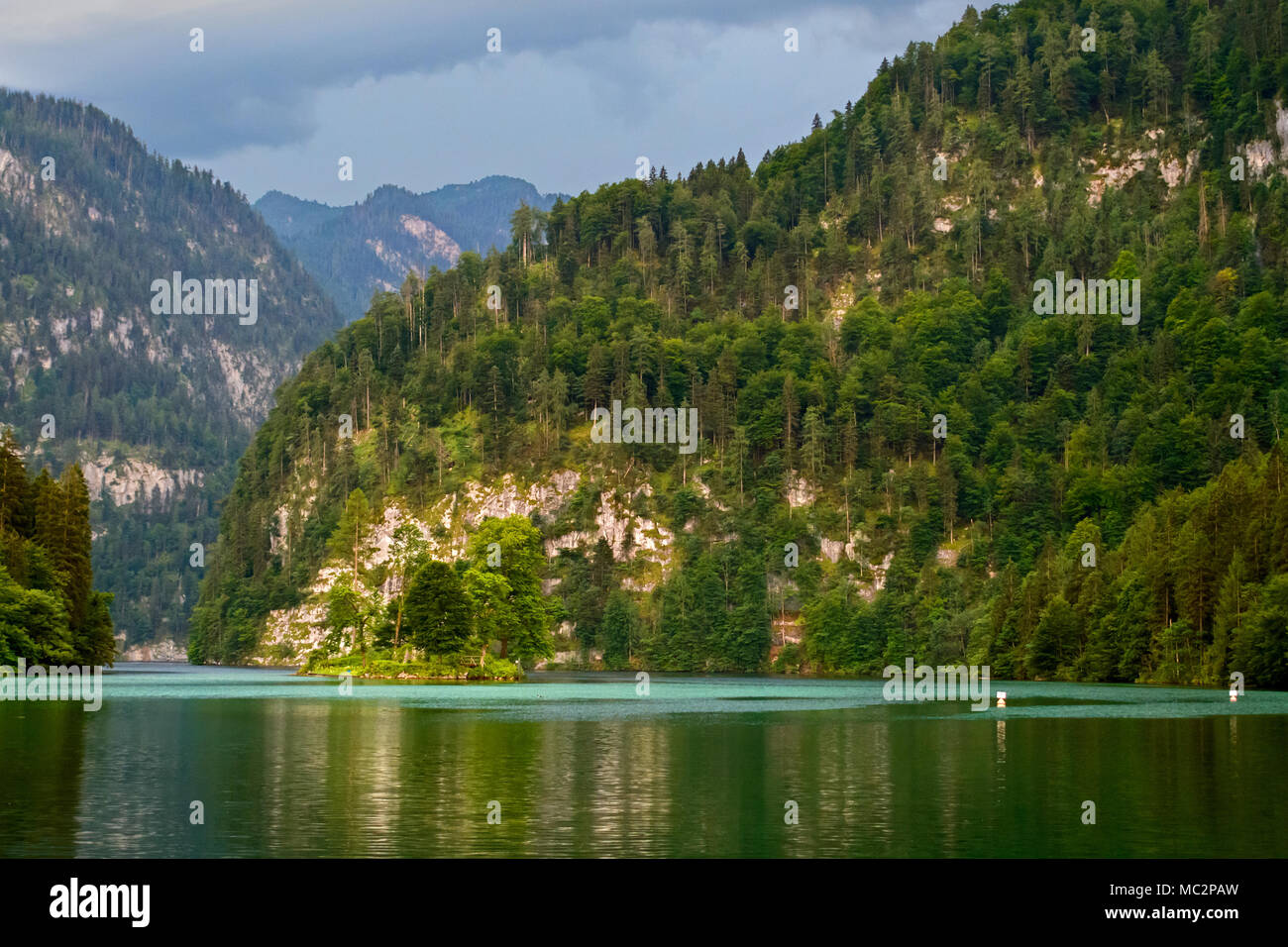 Bewaldete Felsen im alpinen See Wasser spiegelt Stockfoto