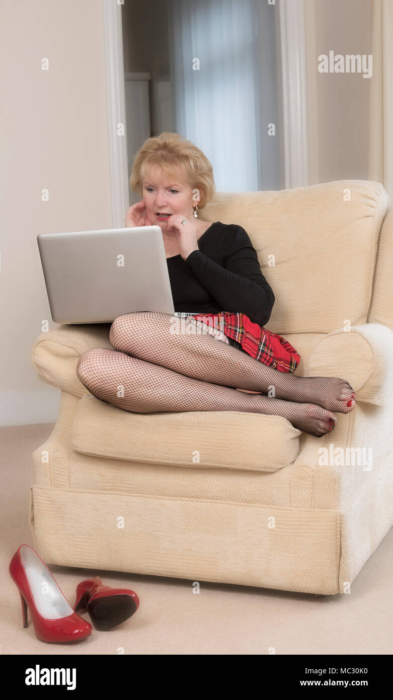Blonde Frau sitzt mit Laptop auf dem Schoß Stockfoto