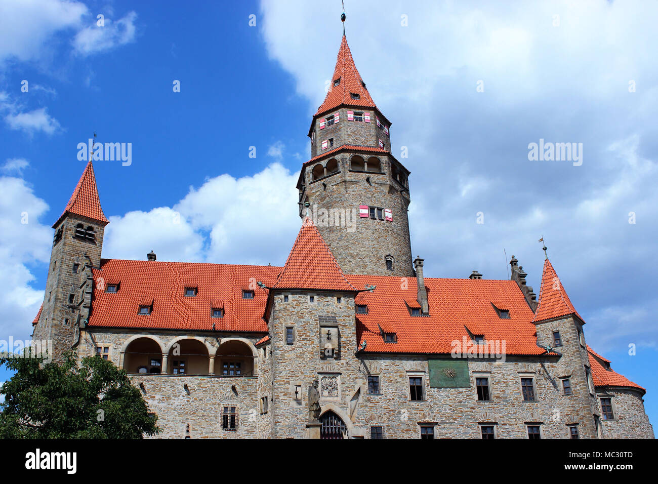Auf dem Foto dominiert die Burg Bouzov und im Hintergrund sehen sie den blauen Himmel mit Wolken. Stockfoto