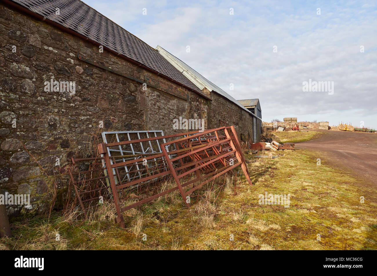 Alte Metall Farm Tore gegen eine Wand von einem Bauernhof aus Stein gebaut gestapelt Nebengebäude mit anderen landwirtschaftlichen Rückstände im Hintergrund, in der Nähe von Dubton, Angus in Schottland Stockfoto
