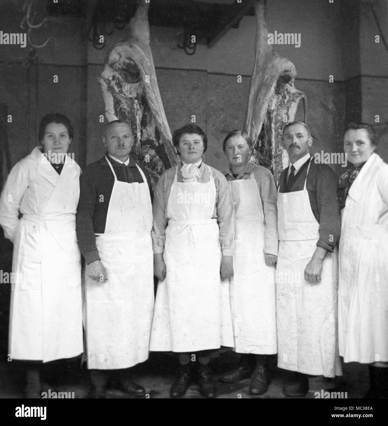 Die Metzgerei Mitarbeiter hängen von den hängenden Fleisch in Deutschland, Ca. 1934. Stockfoto