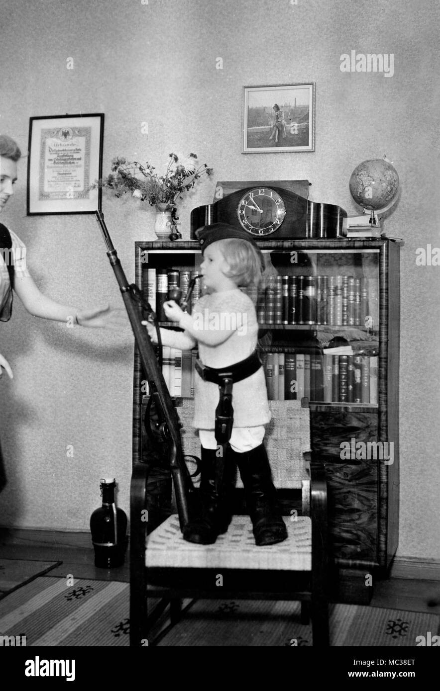 Mama hilft ihrer Tochter ein wenig Deutscher Soldat werden komplett mit Gewehr, Rohr, Stiefel und Dolch, Ca. 1938. Stockfoto