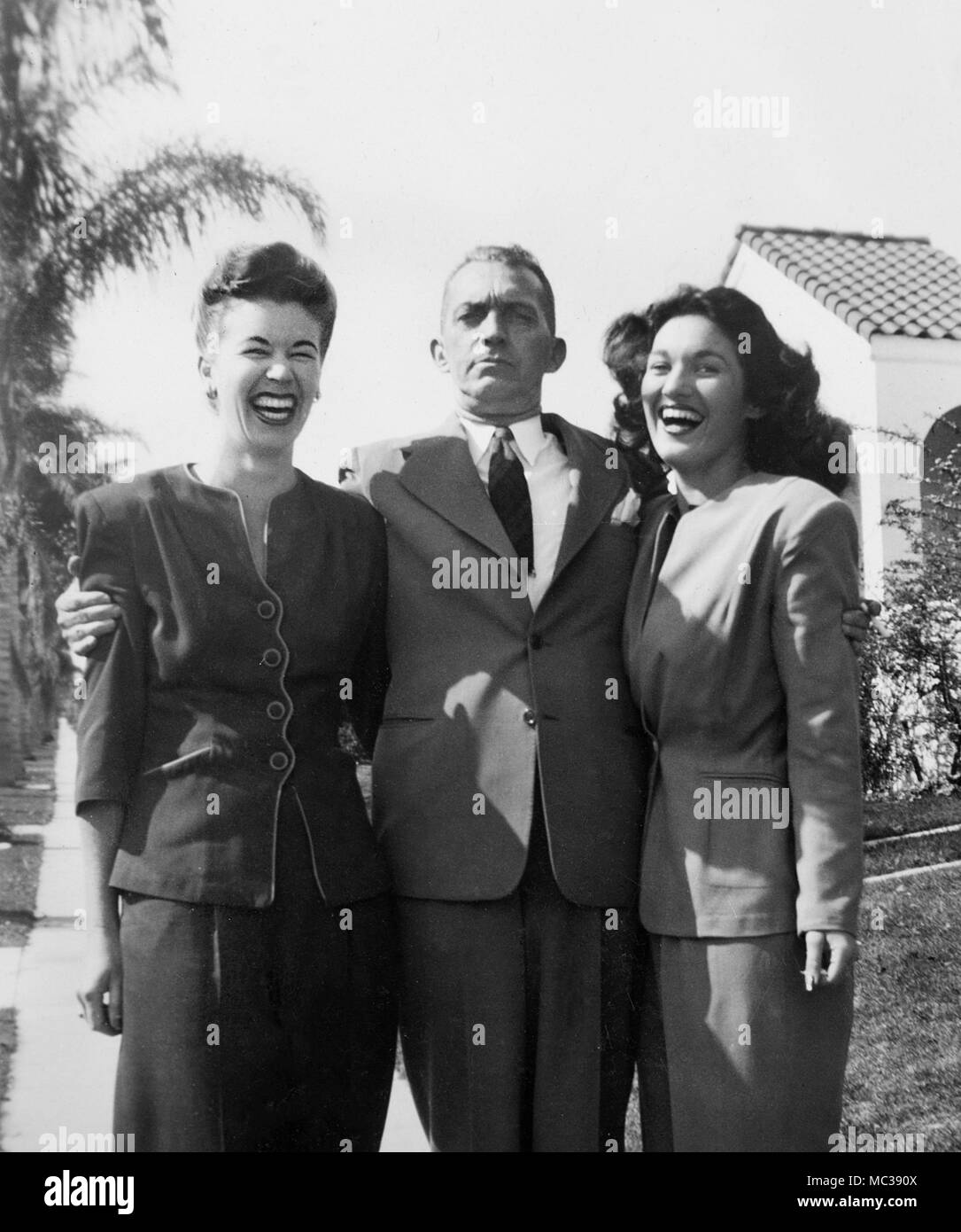 Ein sehr ernster Mann wird von zwei extrem glücklich Frauen, ca flankiert. 1946. Stockfoto