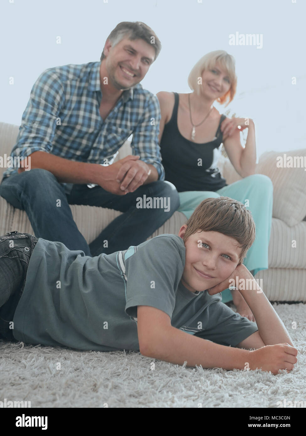 Portrait der Kinder, während die Eltern auf einem Sofa im Wohnzimmer roo Sitzen Stockfoto