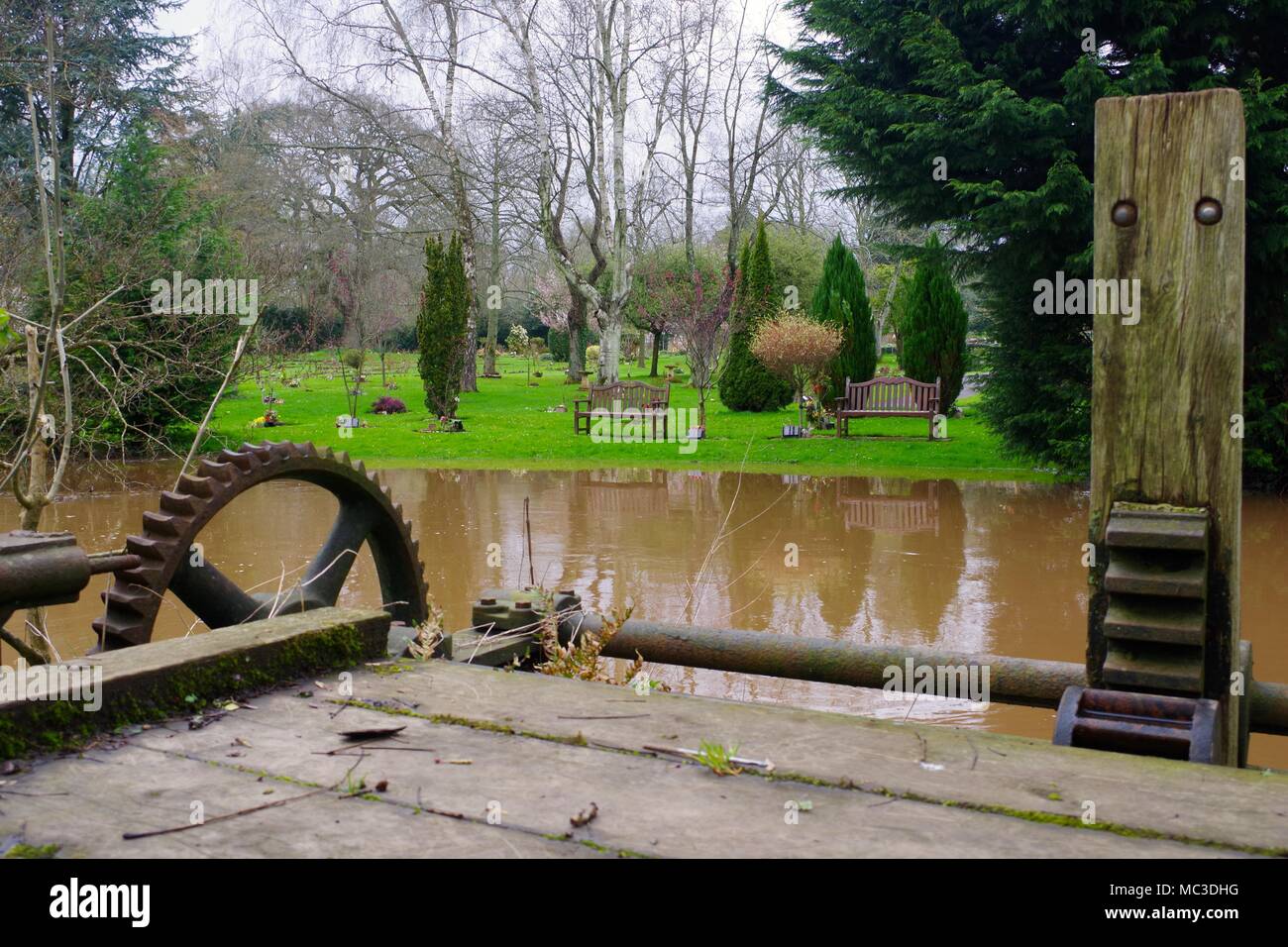 Gräfin Wehr Mühle Gewaehrleistung, viktorianischen Schleuse Tor und Exeter & Devon Krematorium Gärten. River Exe in der Flut. UK. April, 2018. Stockfoto