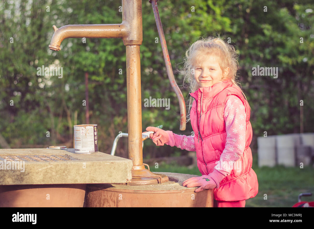 Adorable blonde Mädchen malen Mit Pinsel eine gut im Garten Stockfoto