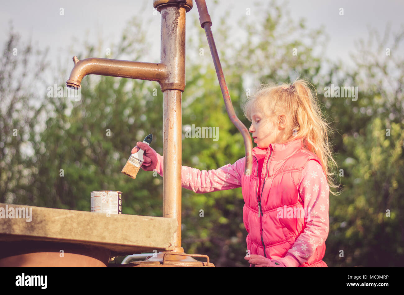 Adorable blonde Mädchen malen Mit Pinsel eine gut im Garten Stockfoto