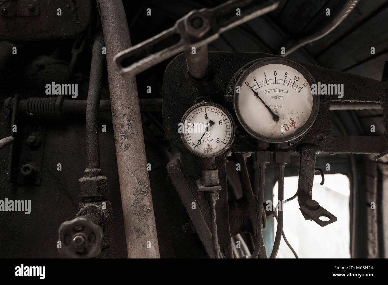 Details der Inneneinrichtung der abgebrochenen alten rostigen sowjetische Lokomotive an der Plattform. Zwei Bremsen vintage Manometer und rostige Rohre. In russischer Sprache auf Weiß Stockfoto