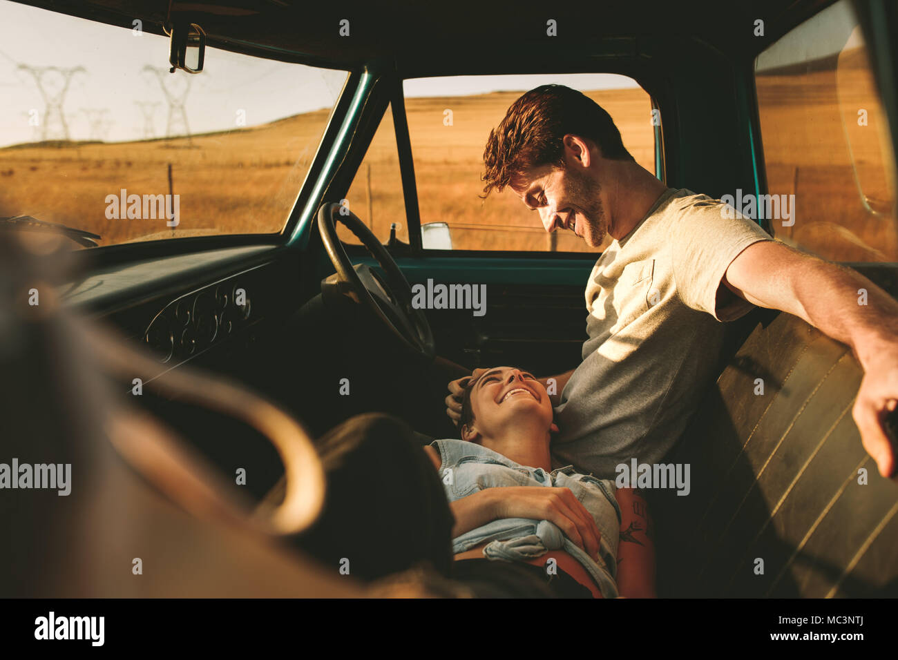 Paar in Ihrem Auto sitzen genießen die Straße Reise im Land. Liegende Frau auf dem Schoss der Mann auf dem Fahrersitz sitzen. Stockfoto