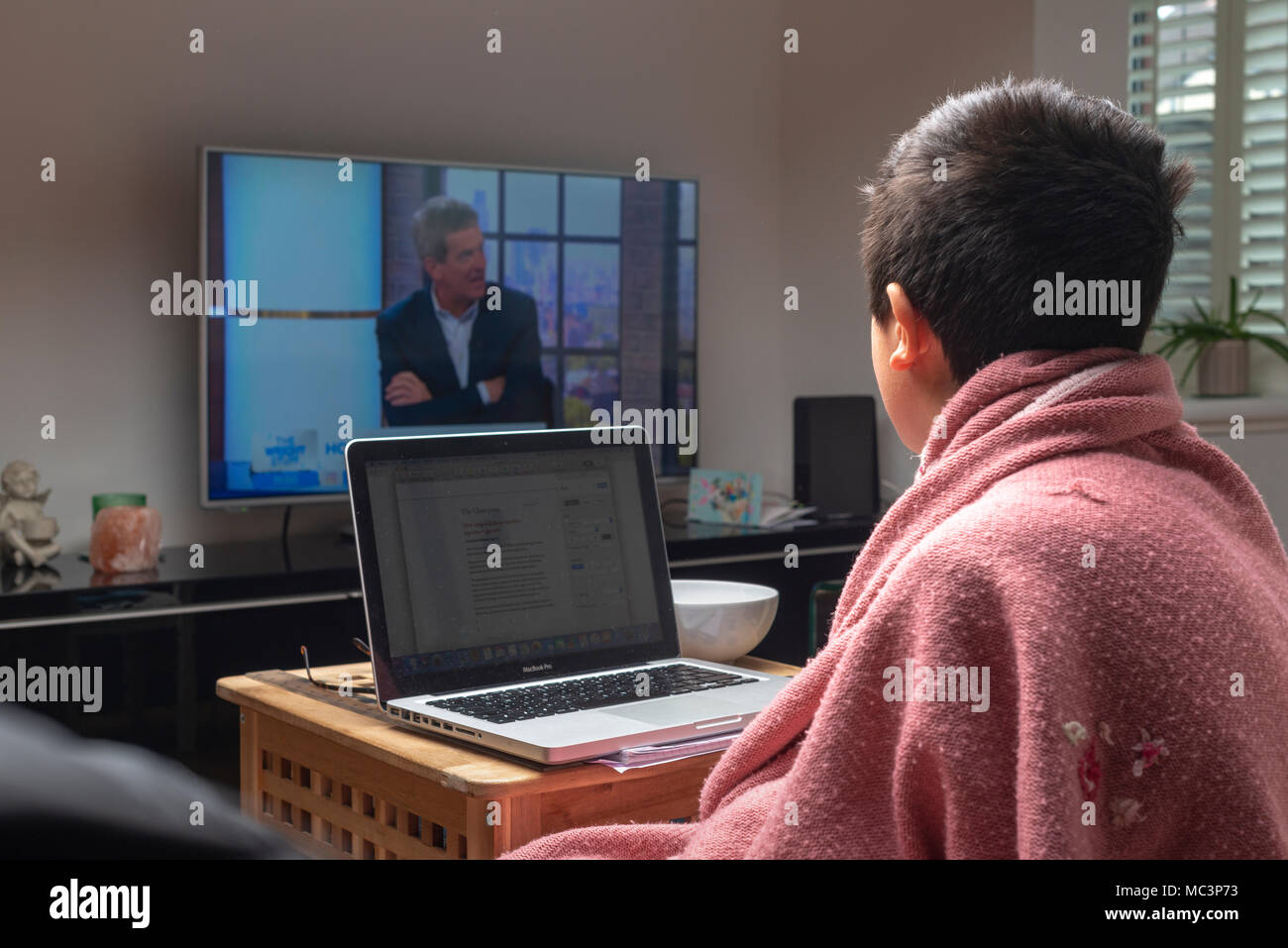 Junge, 10 Jahre alte watrches TV, deckt sich mit einer Decke im kalten Wohnzimmer, Großbritannien Stockfoto