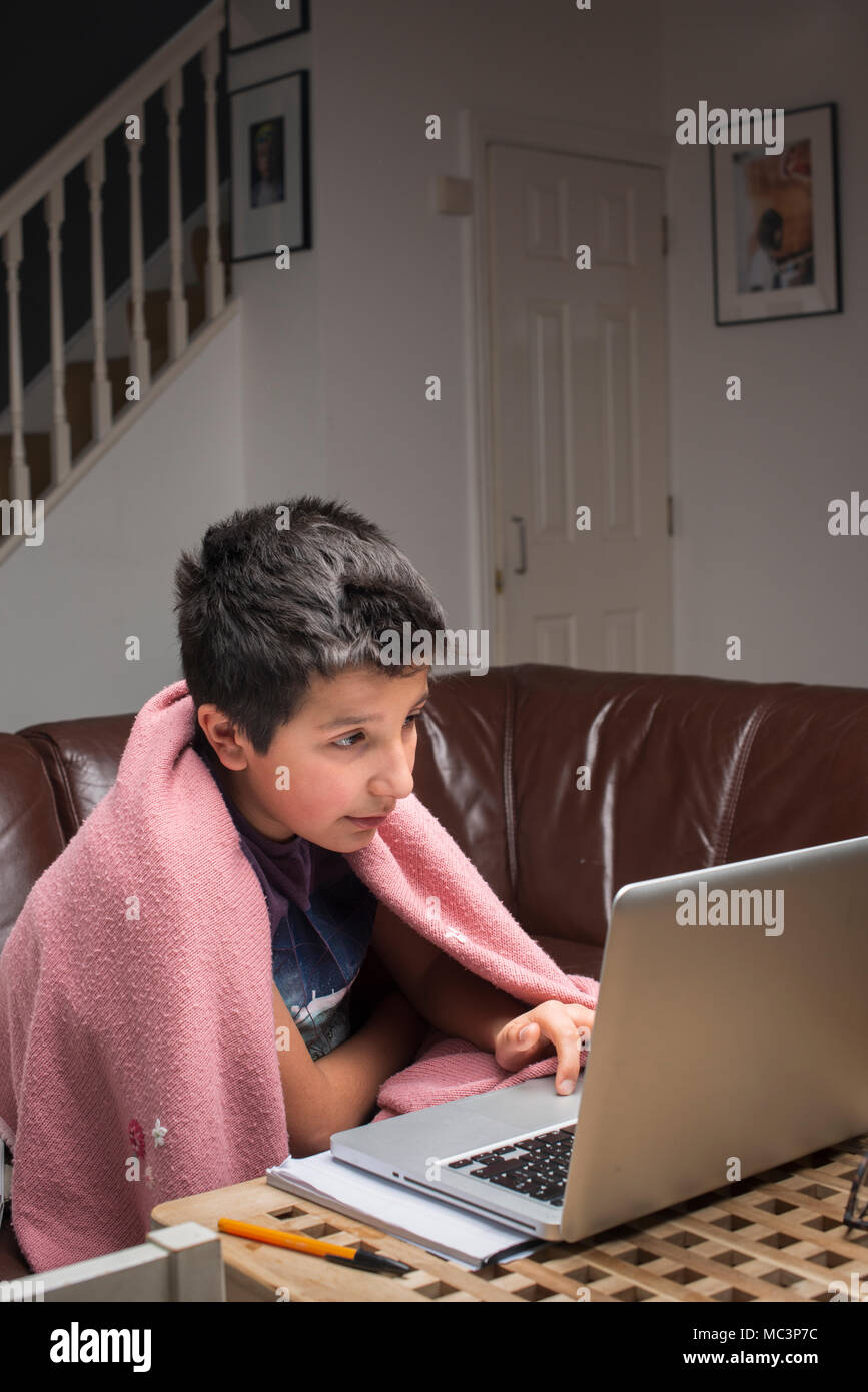 London, Großbritannien. Junge, 10 Jahre alte Studien in seinem Computer in einem kalten Zimmer Stockfoto