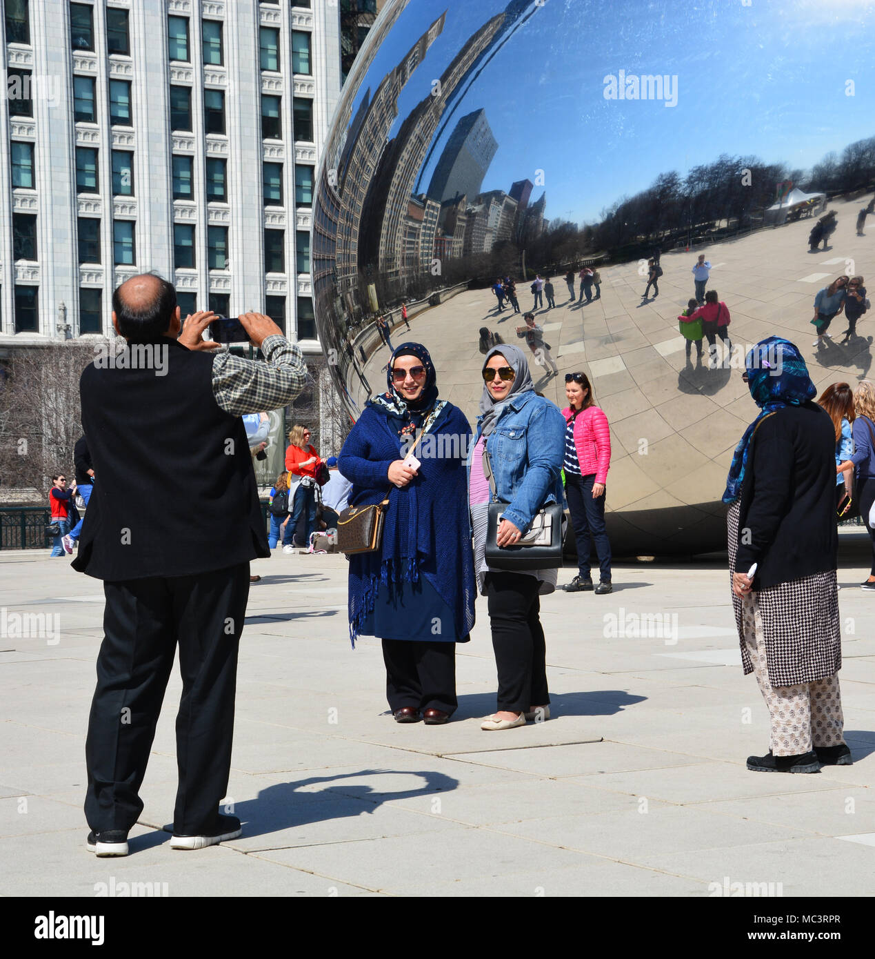 Eine Familie posieren für selfies mit Chicago's 'Bean' im Millennium Park an einem warmen Frühlingstag. Stockfoto