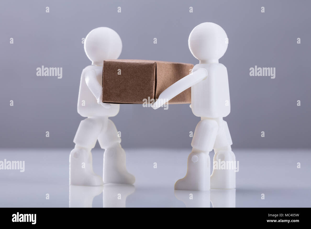 Close-up zwei menschliche Figuren mit Karton gegen grauer Hintergrund Stockfoto