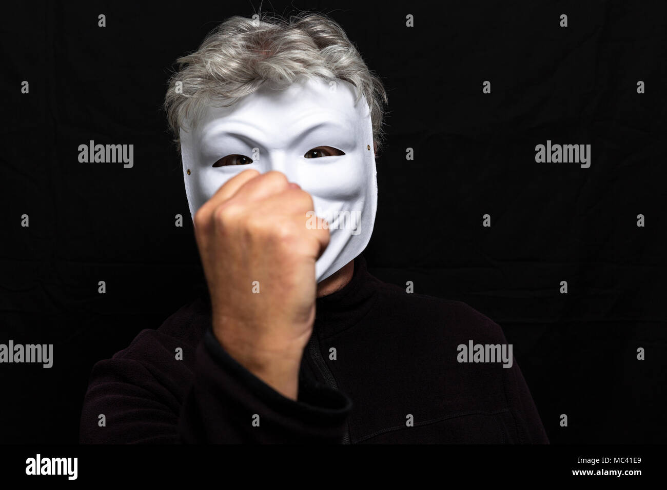 Grauhaariger Mann in anonymen Maske Holding eine Faust Stockfoto