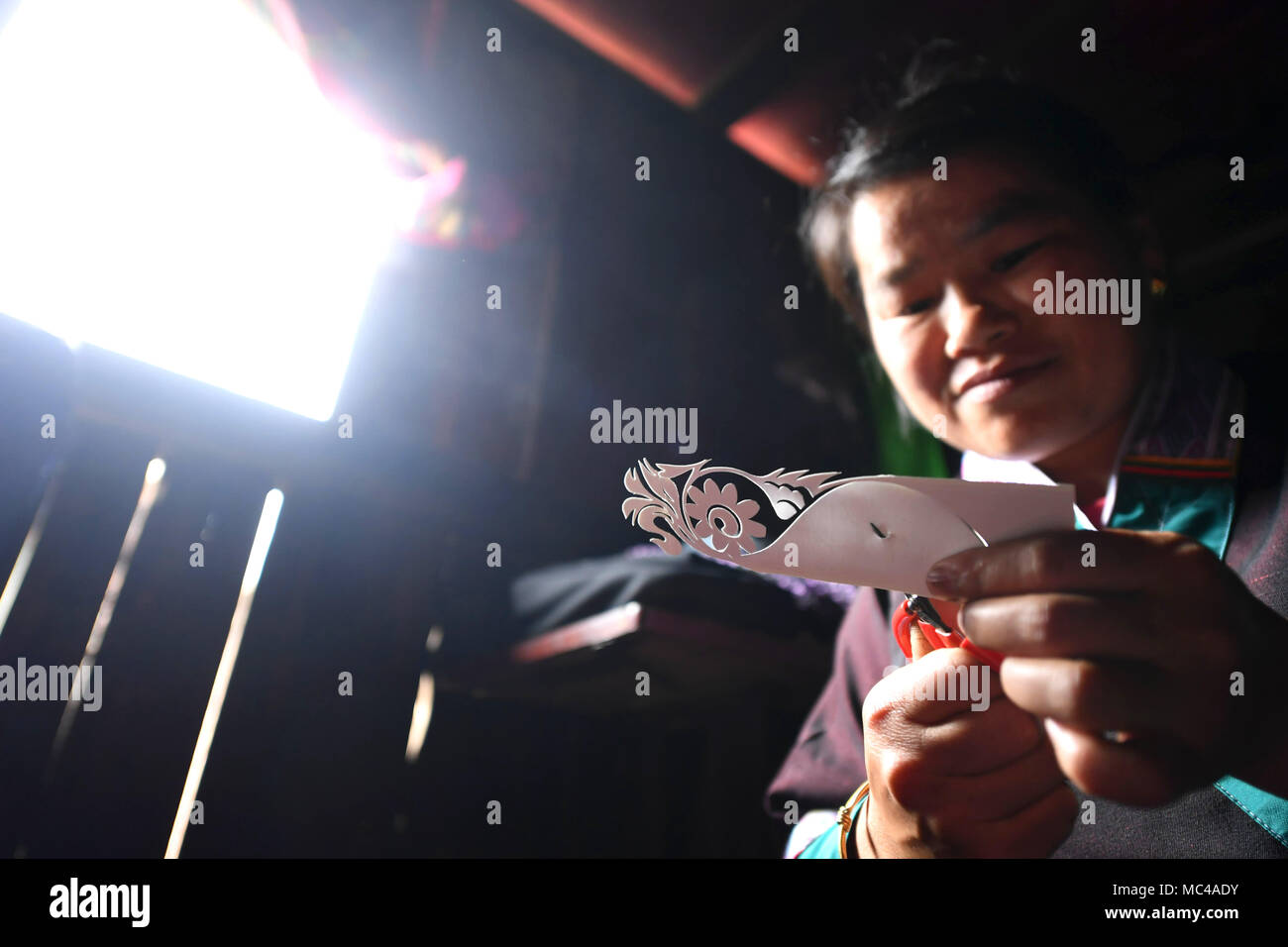 (180413) - SANJIANG, April 13, 2018 (Xinhua) - Gewehr Peiyi macht Papier - Ausschnitte für Stickerei in Yongwei Dorf, Liuzhou Stadt im Süden Chinas Autonomen Region Guangxi Zhuang, 12. April 2018. Trotz taub und stumm, der 43 Jahre alte Waffe ist für ihr Geschick in Stickerei bekannt. Liebevolle Stickerei, da sie jung war, Gewehr, die Meister sowohl Dong und Miao Sticktechniken, erwarb Ruhm, nachdem sie viele Stickerei arbeitet mit vielfältigen Stilen und abstrakte Bilder erstellt. Vor vier Jahren, ihr Ehemann verstorben, so dass sie und ihre Tochter leben Miteinander. Die einheimischen Frauen Stockfoto