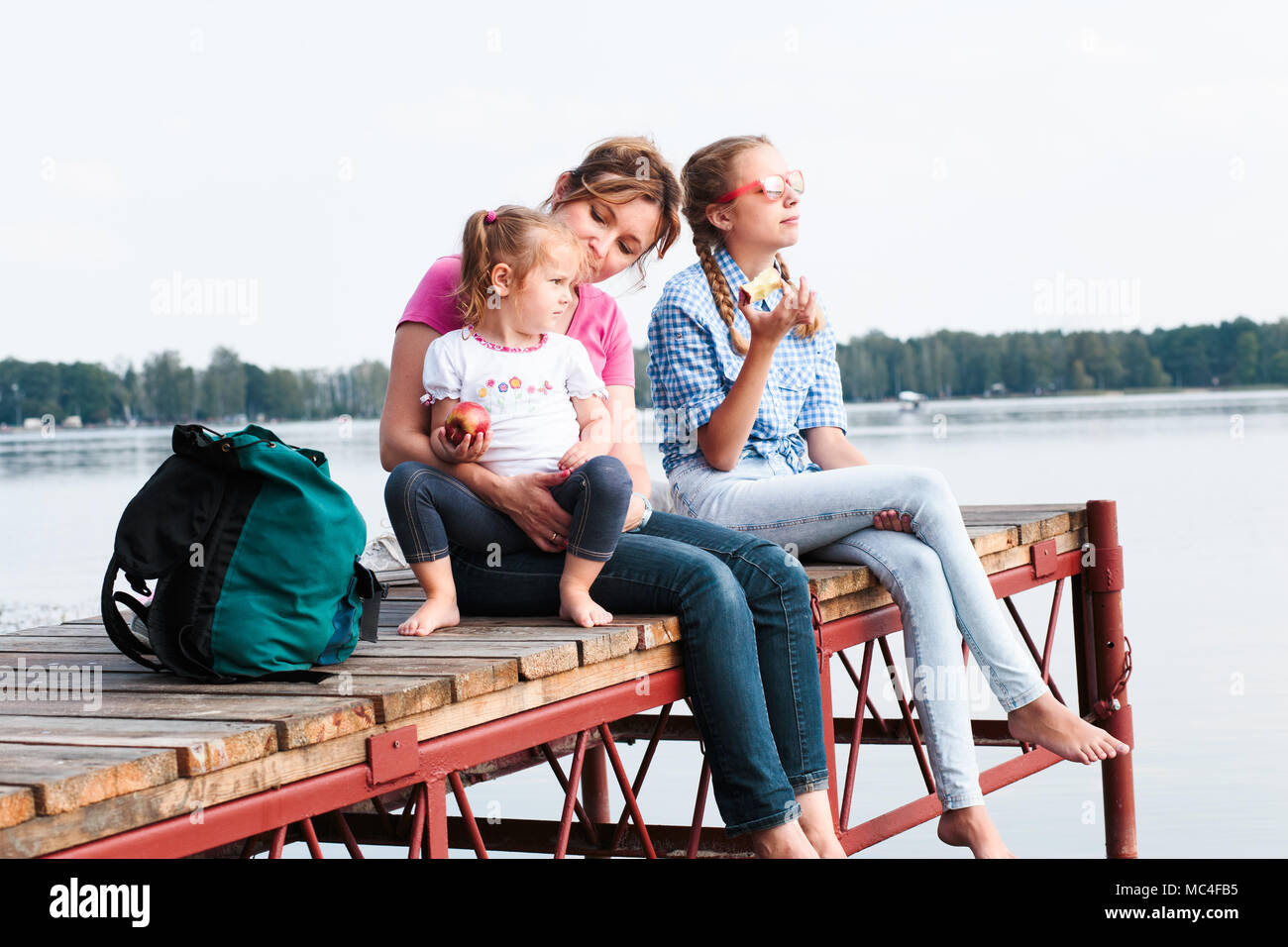 Familie verbringt wenig Zeit zusammen einen Snack am Steg über den See an einem sonnigen Tag im Sommer sitzen. Qualität, Zeit mit der Familie am Wochenende Stockfoto