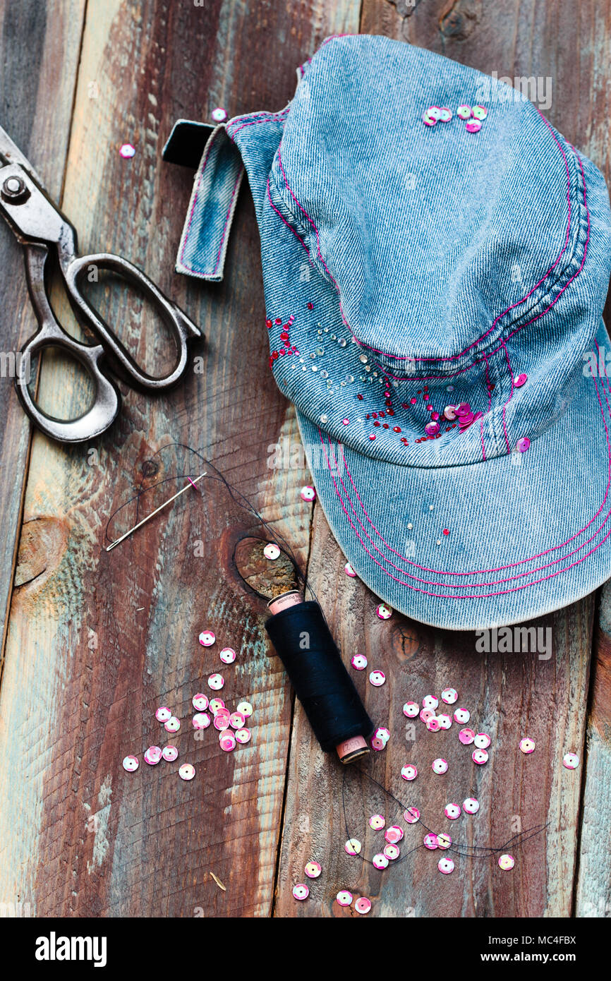 Cap mit Pailletten verziert mit Nadel und Schere nach diy Ideen auf hölzernen Tisch Stockfoto