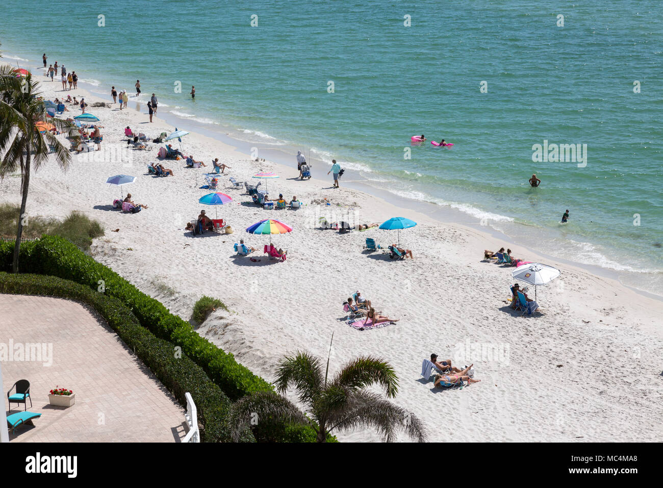 Blick von oben der Strand an der Küste von Florida in Neapel. Familien Urlaub in den Osterferien. Bunte Sonnenschirme. Stockfoto