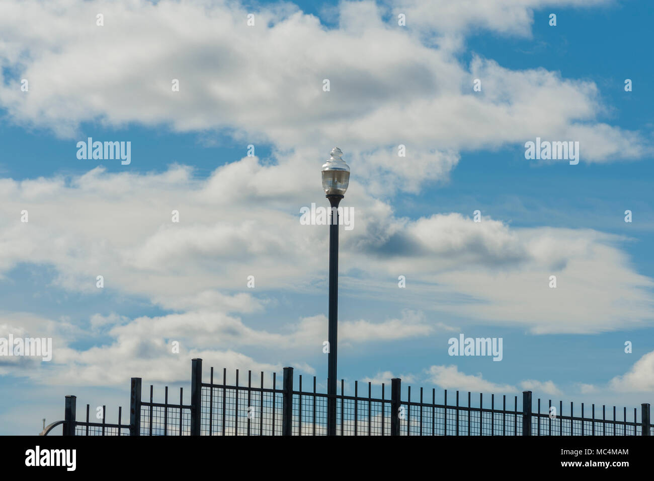 Bewölktem Himmel eine Kulisse für eine einsame Straße Licht und schmiedeeisernen Geländer. Stockfoto