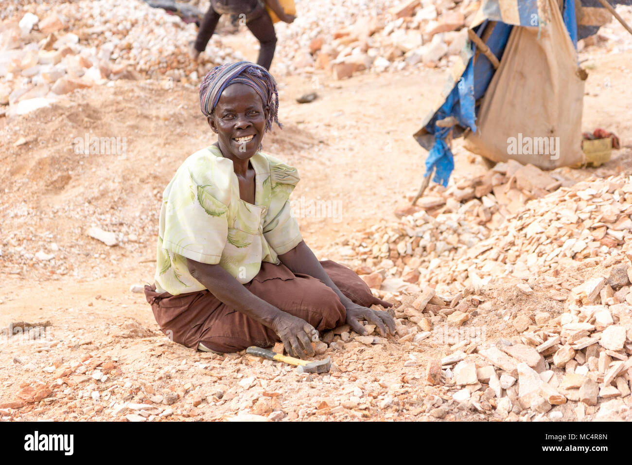 Lugazi, Uganda. 18. Juni 2017. Eine ugandische Frau brechen Steine in kleine Platten für ihren Meister. Stockfoto