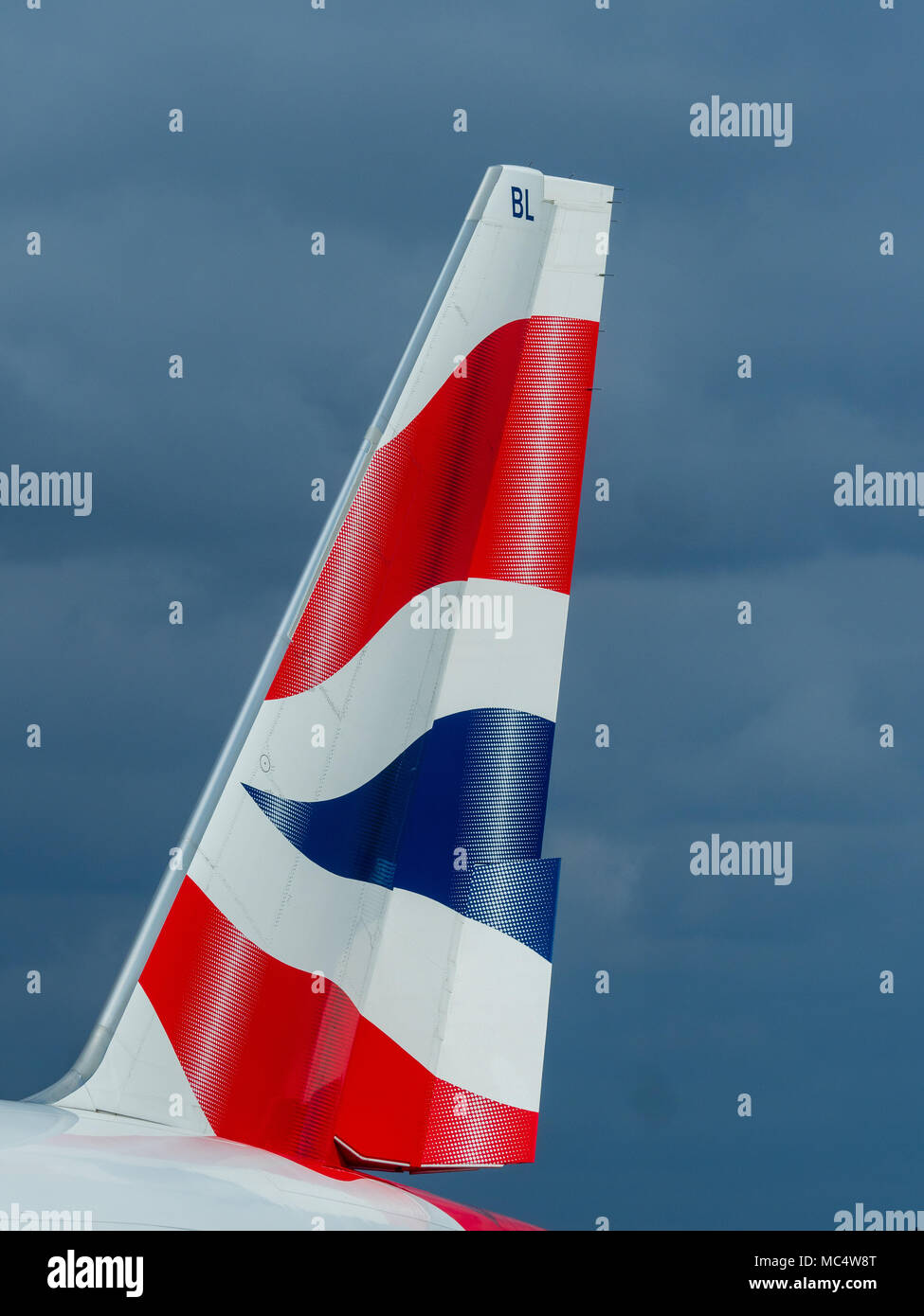 British Airways Schwanzflosse - Schwanzflosse eines BA Boeing 777 gegen dunkle Wolken Stockfoto