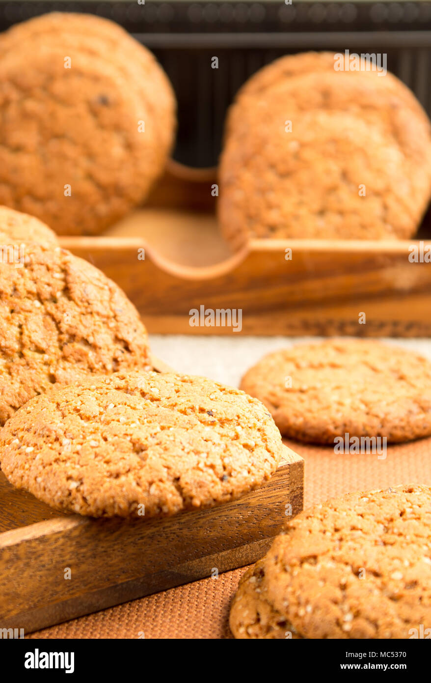 Gruppe von Haferflocken Cookies auf einer hölzernen Fach auf einem braunen Tischdecke mit einer sehr geringen Schärfentiefe Stockfoto