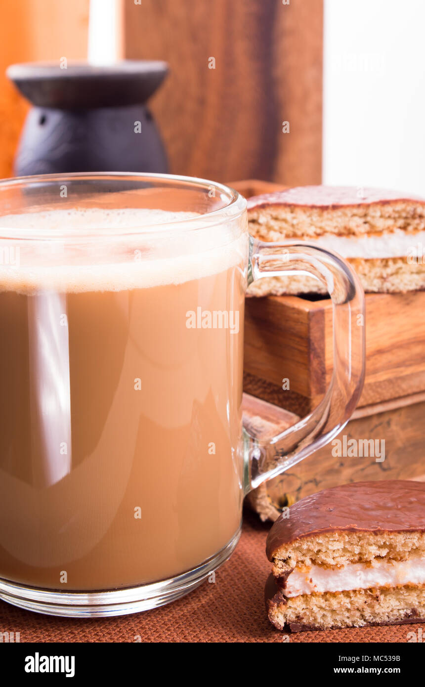 Glastasse Kakao auf einem Tisch in der Nähe mit alten Buch und Schokolade Kekse auf einem Holztablett mit geringen Schärfentiefe Stockfoto