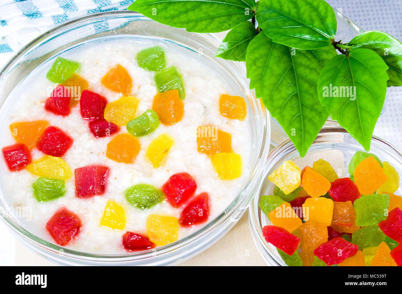 Glasschale mit gesunden Haferflocken Nahaufnahme mit bunten kandierten Früchte zum Frühstück wird durch Sonneneinstrahlung vom Fenster beleuchtet. Stockfoto